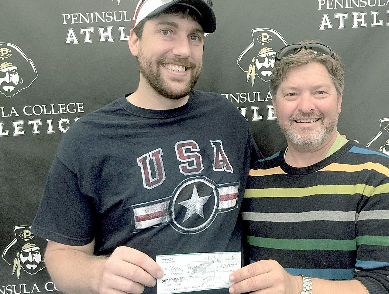 Port Angeles’ Kyle Trussell, left, receives a $2,000 check from Super Cup soccer derby commissioner Tim Tucker. The July 16 event pitted past and current Sequim and Port Angeles players against each other in a community soccer celebration and fundraiser for Trussell, who was badly injured by a bulldozer in a workplace incident last September. Port Angeles rallied to edge Sequim 4-3 in overtime.