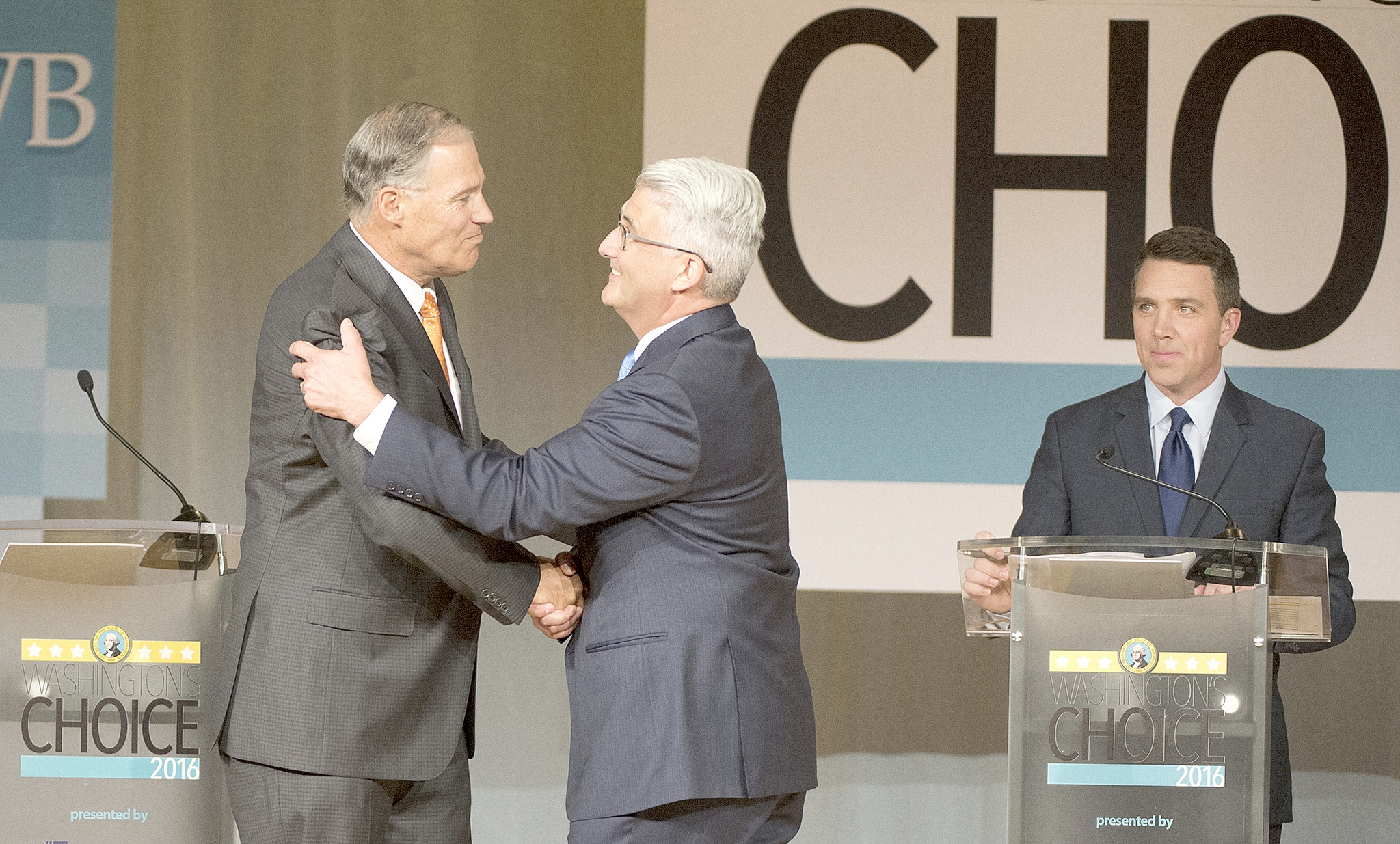 Jesse Tinsley/The Spokesman-Review via AP Washington Gov. Jay Inslee, left, shakes hands with challenger Bill Bryant before the two debate at Spokane Falls Community College on Wednesday in Spokane. Moderator Sean Owsley of KHQ-TV stands at right.