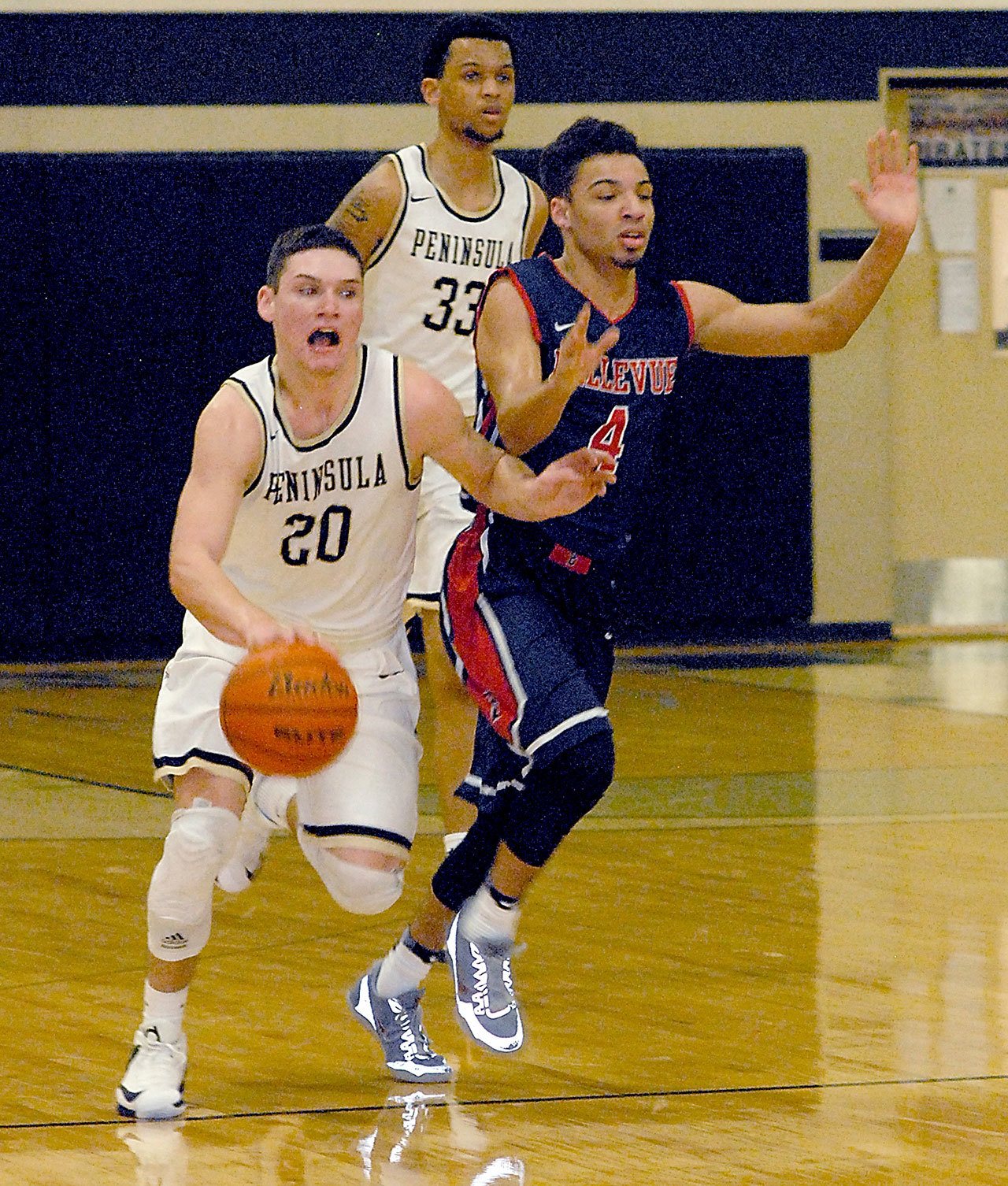 Keith Thorpe/Peninsula Daily News Peninsula’s Cole Rabedeaux, left, drives downcourt in front of Bellevue’s Trey Nelson in the first half on Saturday in Port Angeles. Following behind is Peninsula’s Kevin Baker.