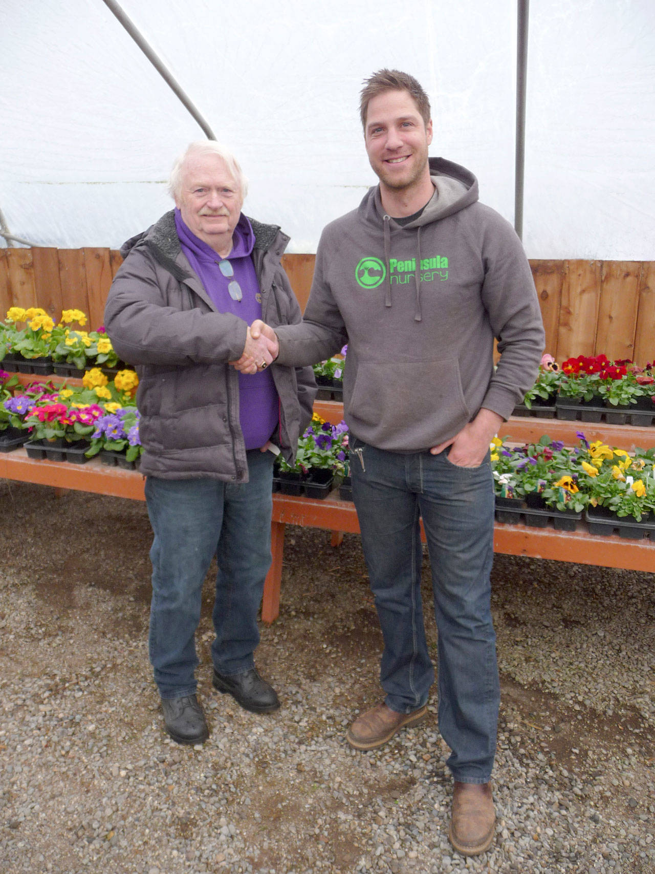 Roger Fell, left, a longtime nurseryman and owner of Peninsula Nurseries, shakes hands with George Peterson, who has purchased the business and the property. (Patricia Morrison Coate/Olympic Peninsula News Group)