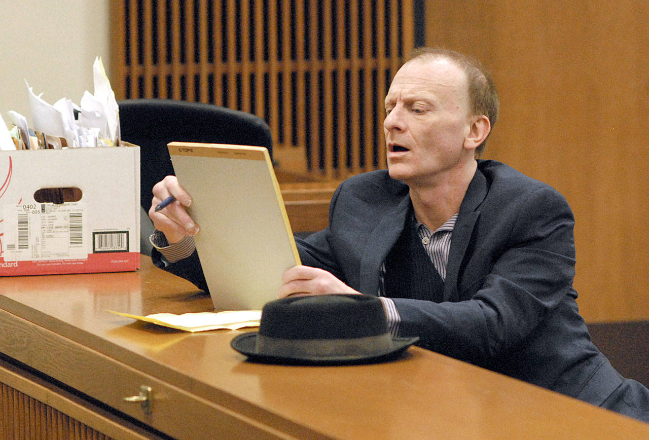 John Greystoke of Port Angeles examines a notepad during his trial for first-degree assault during his Thursday appearance in Clallam County Superior Court. (Keith Thorpe/Peninsula Daily News)