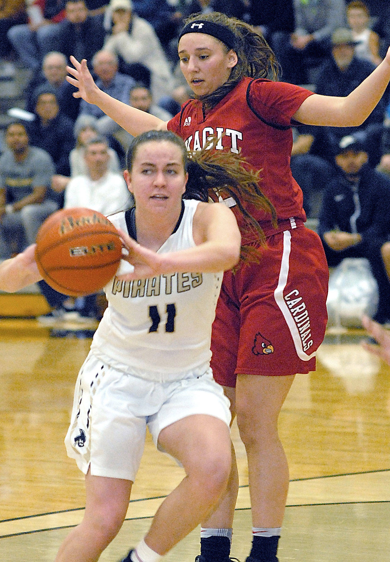 Peninsula’s Ashlynn Sharp, front, passes the ball as she slips around Skagit Valley’s Brook Geffe in the third quarter Wednesday night in Port Angeles. Keith Thorpe/Peninsula Daily News