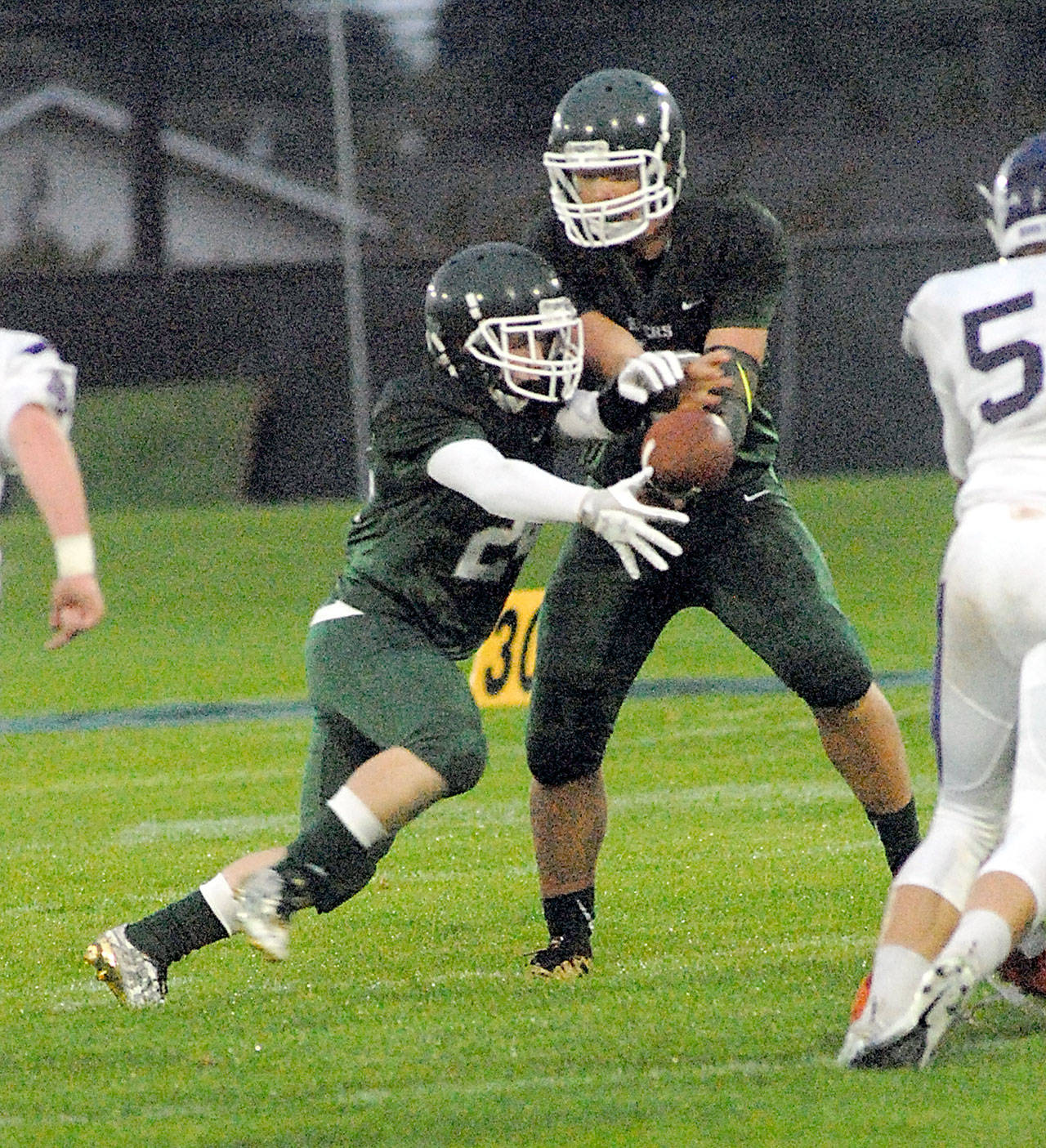 Keith Thorpe/Peninsula Daily News Port Angeles quarterback Brenden Roloson-Hines hands off to running back Trevor Shumway in the first quarter against North Thurston on Friday night at a rainy Port Angeles Civic Field.