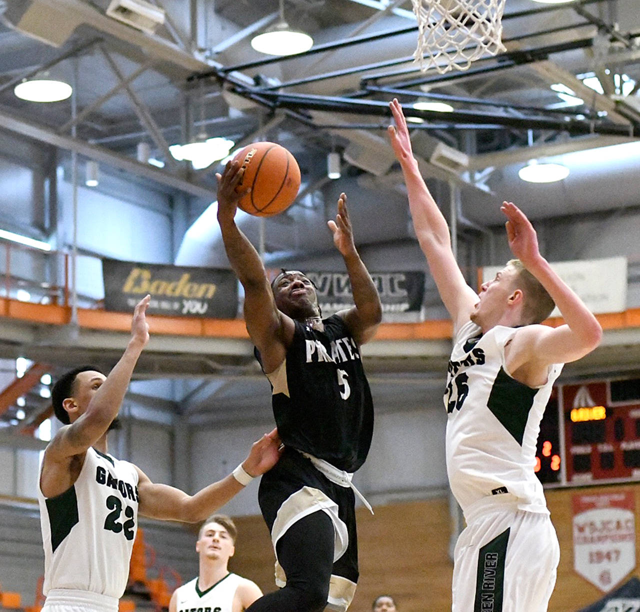 Peninsula’s Nyair Cleveland attempts a layup while defended by Green River’s Kevin Baker, left, and Alex Sommerfield during the Pirates’ 89-66 NWAC Tournament defeat Thursday in Everett.                                Jay Cline