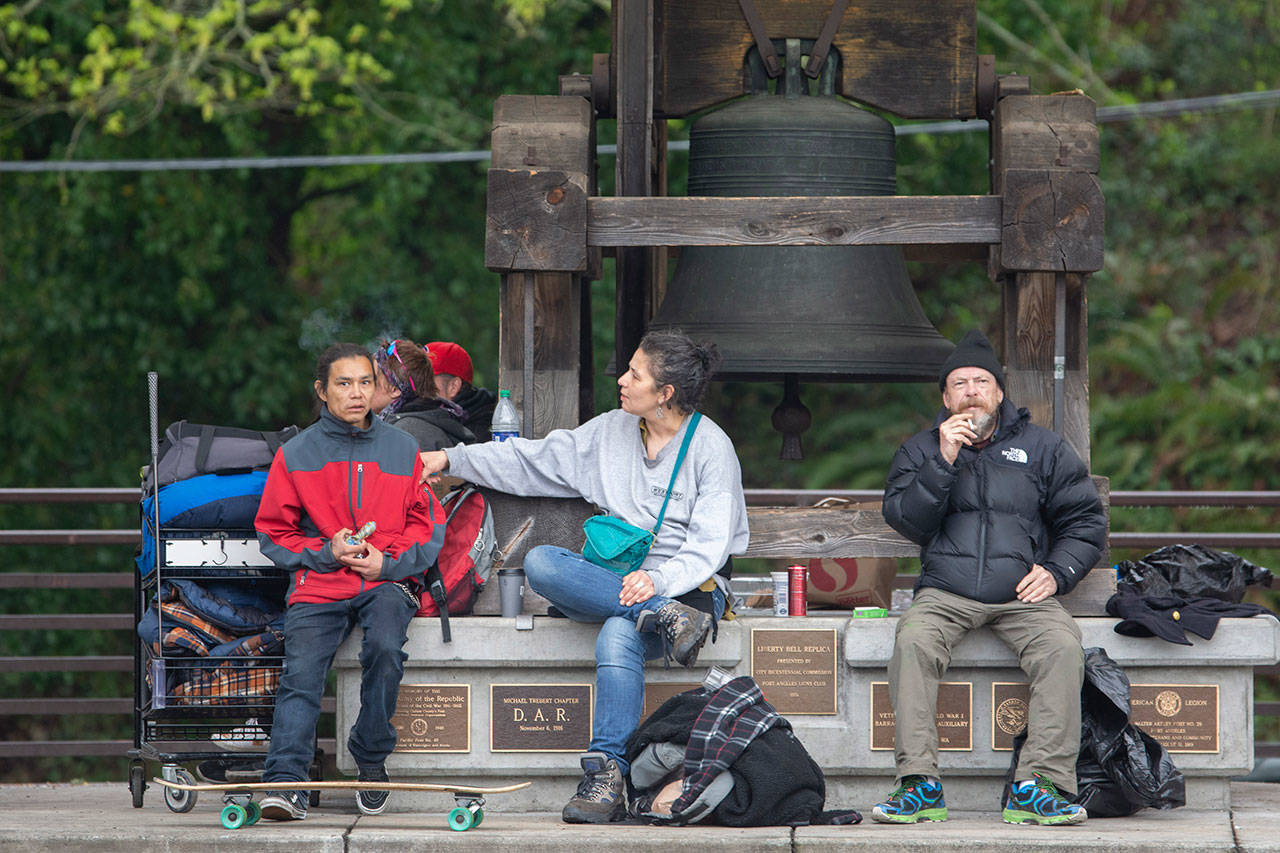 People sit around the Liberty Bell at Veterans Memorial Park in Port Angeles. (Jesse Major/Peninsula Daily News)