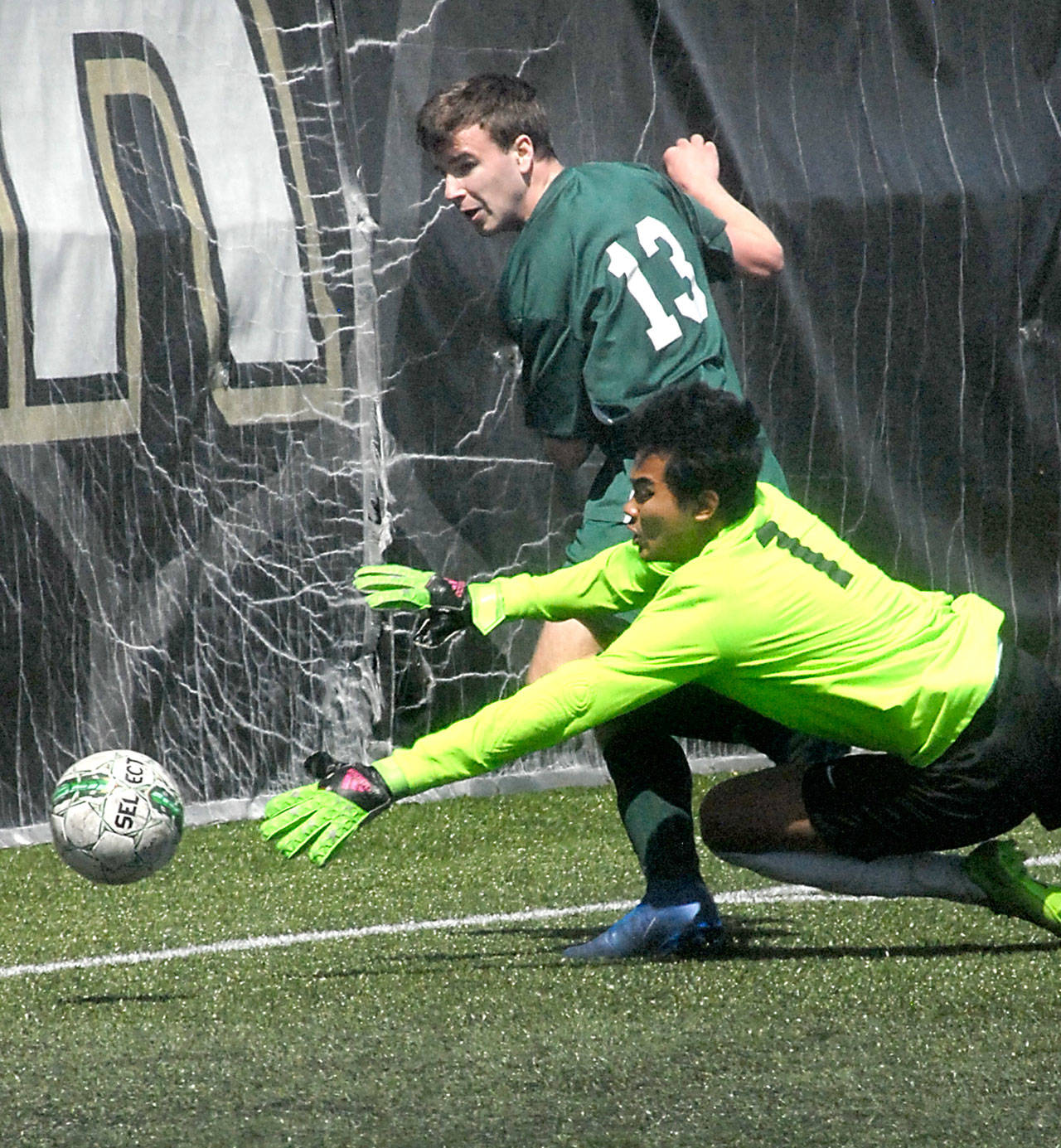 Keith Thorpe/Peninsula Daily News Port Angeles’ Stuart Methner, top, slips the ball past Foster goalkeeper Sao Lar for a Roughrider point in the first half of Saturday’s playoff game at Peninsula College in Port Angeles.