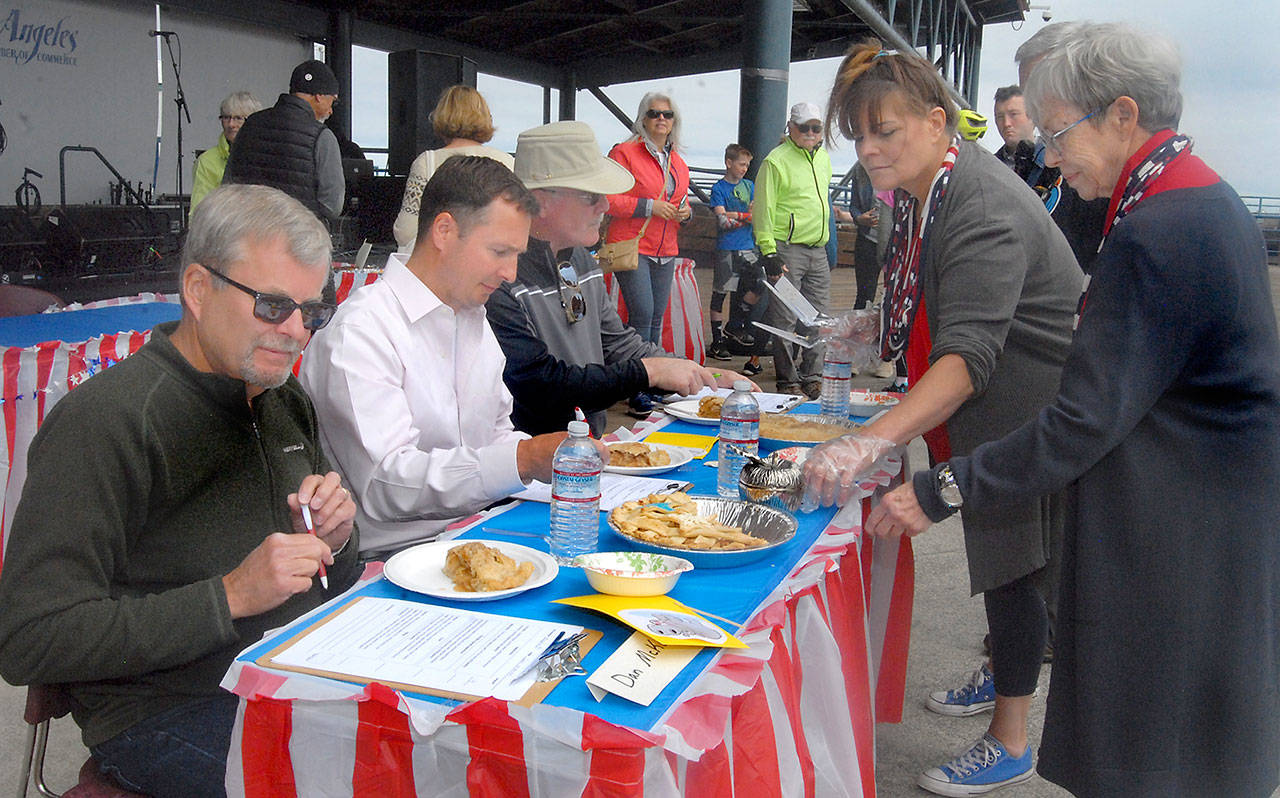 Pie contest judges, from left, former Port Angeles City Manager Dan McKeen, Clallam County Prosecuting Attorney Mark Nichols and former Port Angeles police Chief Terry Gallagher receive slices from organizers Leslie Robertson and Edna Peterson, right, during Thursday’s pie rivalry between the Port Angeles fire and police departments. (Keith Thorpe/Peninsula Daily News)