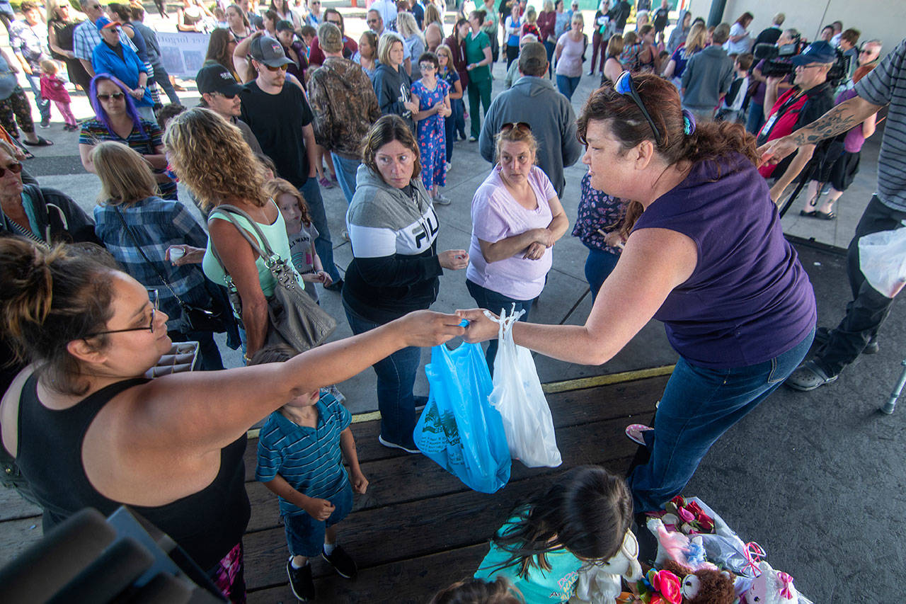 Holly Wright, a friend of Valerie Kambeitz and her children Lilly, Emma and Jayden Kambeitz, hands out candles during a vigil in their honor Monday. (Jesse Major/Peninsula Daily News)