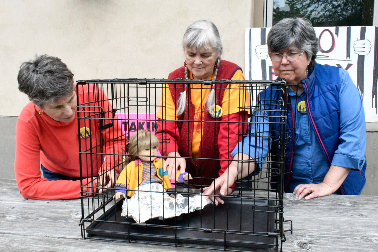 Jefferson County Immigrant Rights Advocates members Jean Walat, left, Julia Cochrane and Linda Murphy put together a display that calls attention to child detention at the southern border. The women will bring the Lights for Liberty: A Vigil to End Detention Camps protest to Jefferson County on Friday. (Jeannie McMacken/Peninsula Daily News)