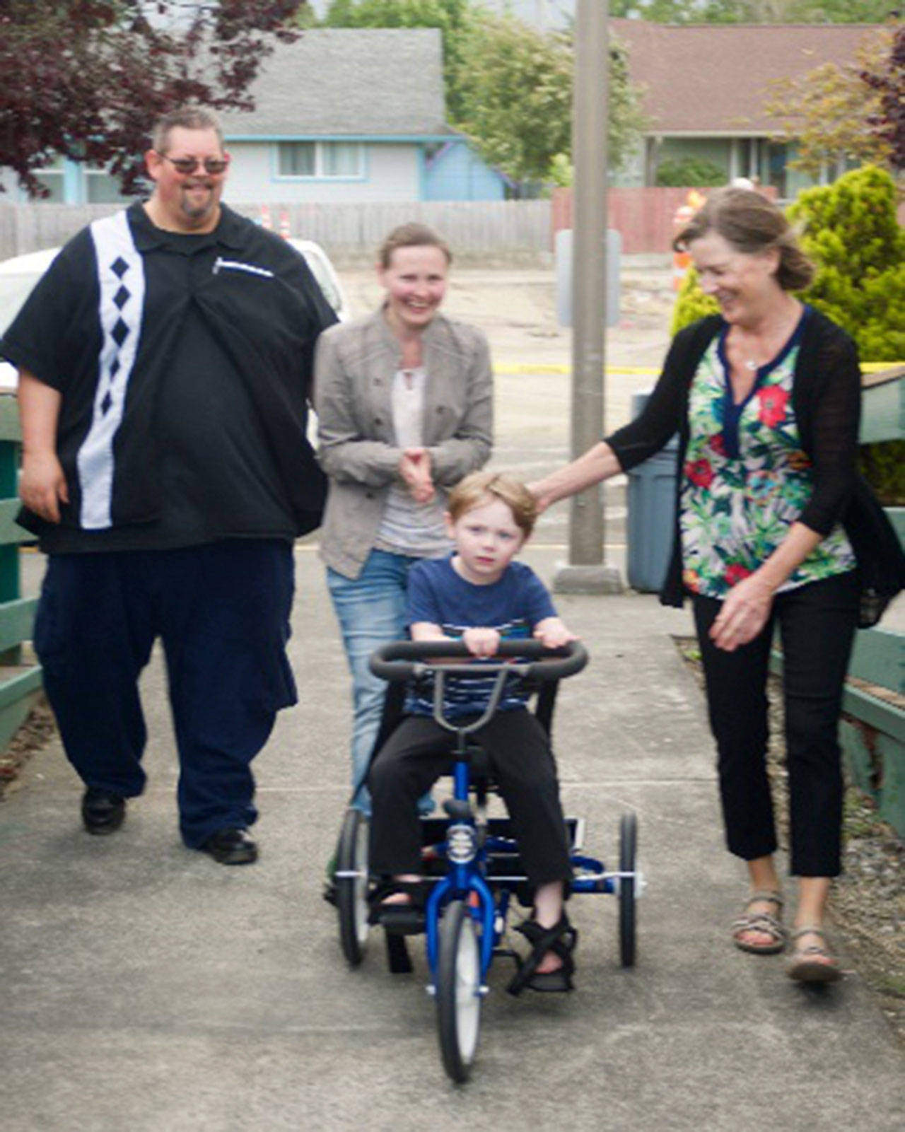 Parents George and Ludmilla Rodes look on as physical therapist Cherry Bibler, right, helps Niko Rodes, 4, adjust to the feel of pedaling the specialized Rifton tricycle. (Doug Schwarz)