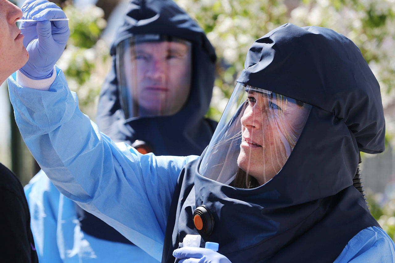 In this Friday, April 10, 2020 file photo, public health nurse Lee Cherie Booth conducts a test for COVID-19 outside of the Salt Lake City Public Health Center, accompanied by Salt Lake County infectious disease nurse Travis Langston. When a swab test comes back positive, contact tracing starts. Local health departments try to reach and assess everyone a person has come in contact with from two days before symptoms to the time test results come back. Experts say contact tracing is key to getting the pandemic under control. (Scott G. Winterton/The Deseret News via AP)