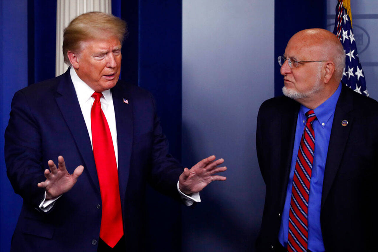 President Donald Trump speaks about the coronavirus in the James Brady Press Briefing Room of the White House on Wednesday, April 22, 2020, in Washington, as Dr. Robert Redfield, director of the Centers for Disease Control and Prevention, listens. (Alex Brandon/Associated Press)