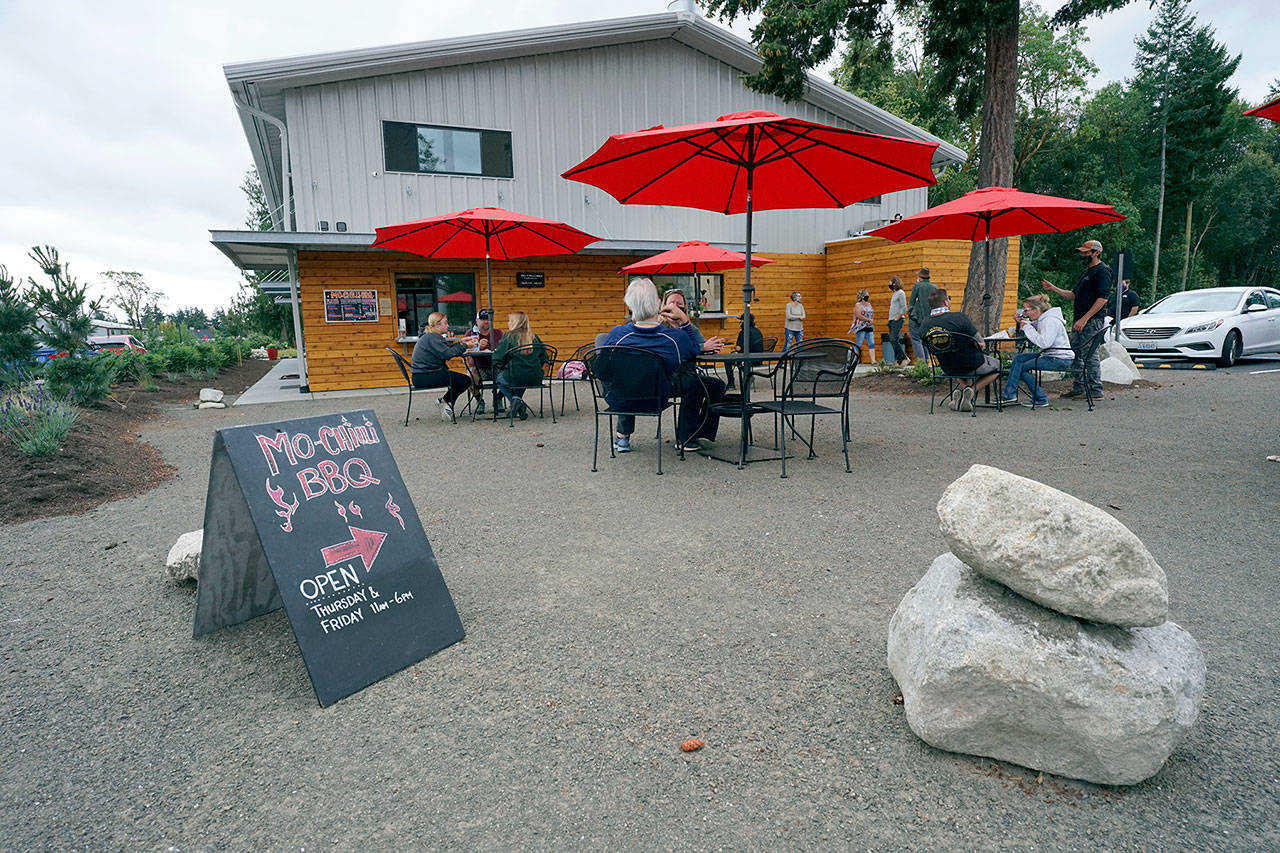 Hungry customers fill the outdoor seating area Friday at Lila’s Kitchen as Mo-Chilli BBQ and The Guerrilla Kitchen take orders and serve food through separate walk-up windows. (Nicholas Johnson/Peninsula Daily News)