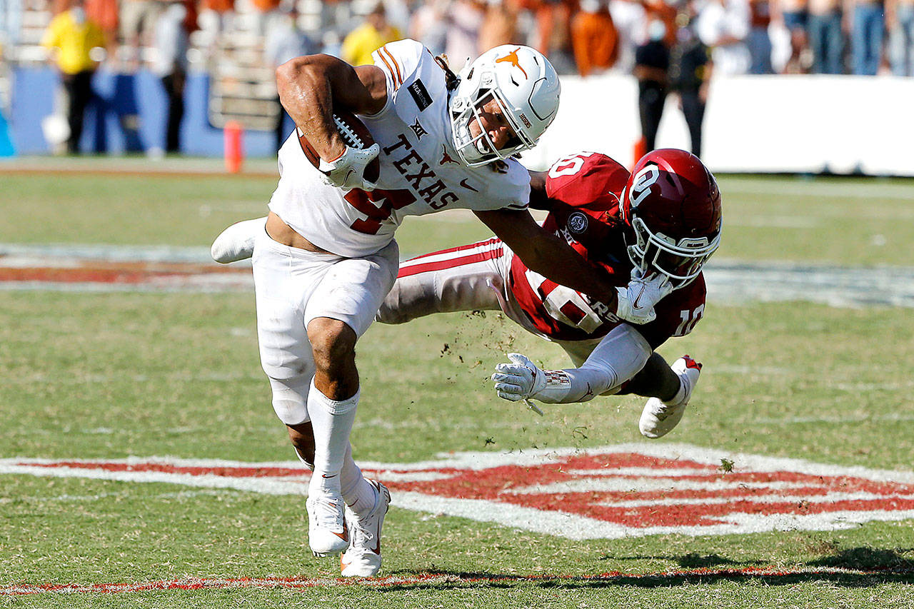 Texas wide receiver Jordan Whittington (4) tries to break a tackle from Oklahoma defensive back Pat Fields (10) during overtime in Dallas on Saturday. Oklahoma defeated Texas 53-45 in four overtimes. (AP Photo/Michael Ainsworth)