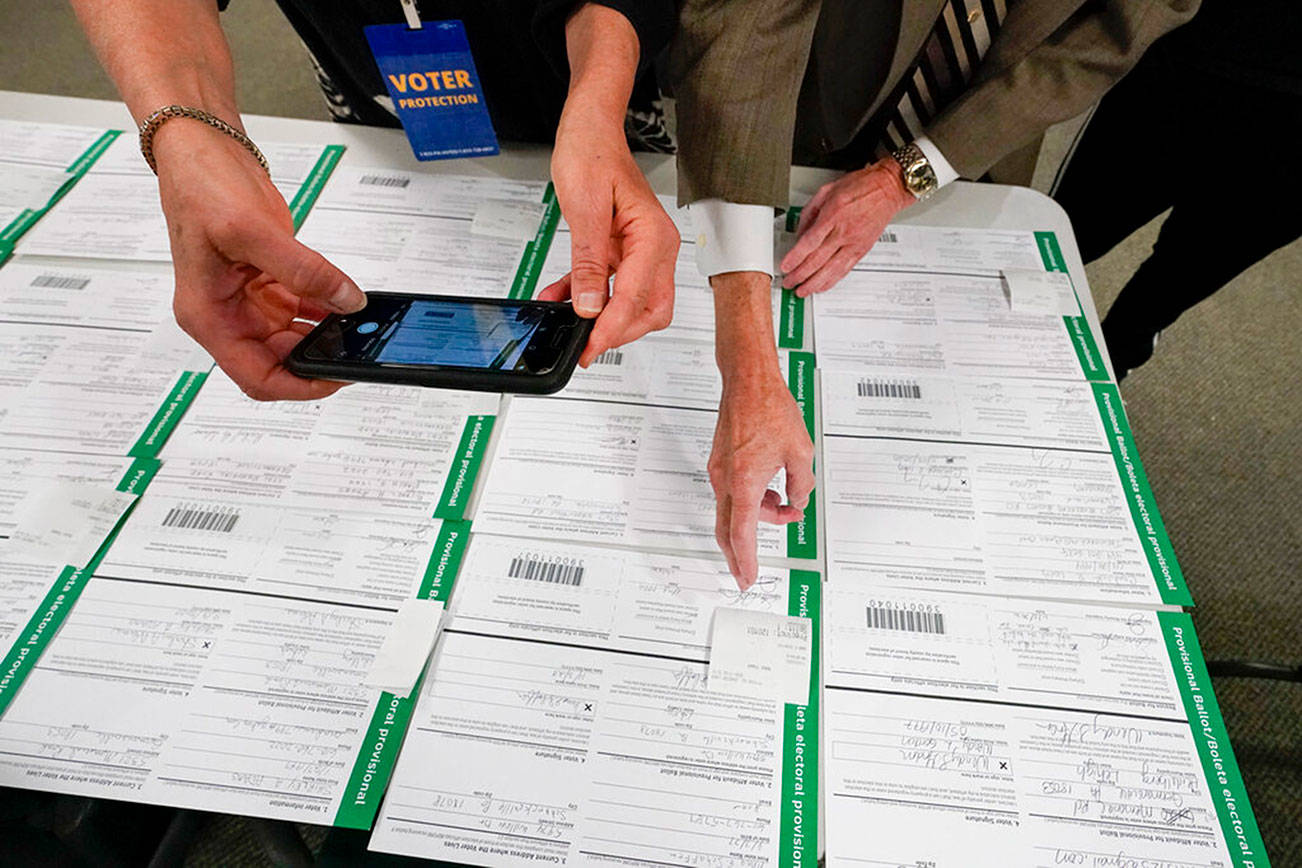 A canvas observer photographs Lehigh County provisional ballots as vote counting in the general election continues, Friday, Nov. 6, 2020, in Allentown, Pa. (AP Photo/Mary Altaffer)