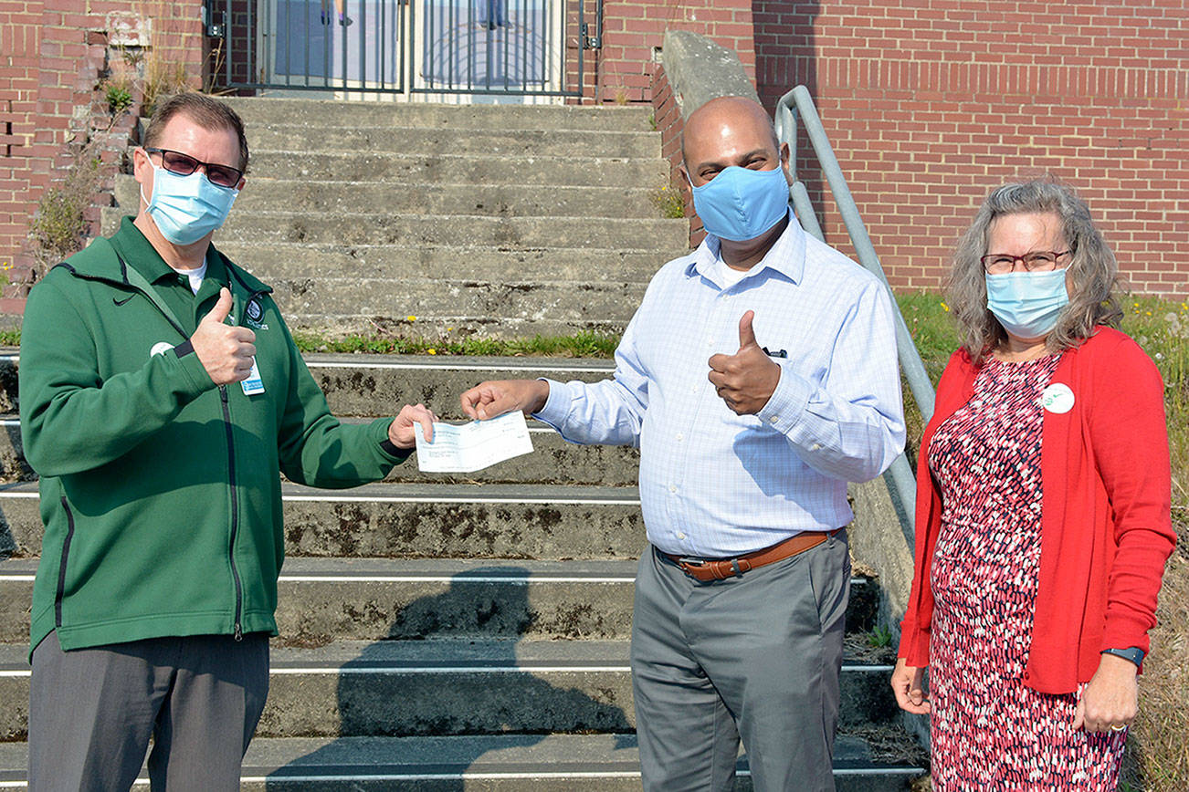 Superintendent Marty Brewer, on left, receives a check from Ray Chirayath, center, and Lynn Bedford, on right, of the Port Angeles Education Foundation. The $50,000 grant will assist students who have difficulty accessing the internet from home in order to participate in distance learning.