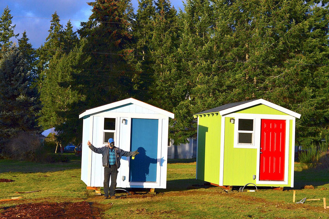 Volunteer builder Randy Welle prepares to welcome people to the Bayside Housing village in Port Hadlock. The sky-blue shelter is named Beth’s House in honor of cofounder Peter Bonyun’s late wife Beth Lorber. (Diane Urbani de la Paz/Peninsula Daily News)