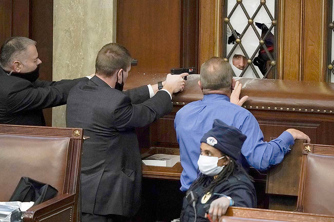 Police with guns drawn watch as protesters try to break into the House Chamber at the U.S. Capitol on Wednesday in Washington, D.C. (J. Scott Applewhite/The Associated Press)