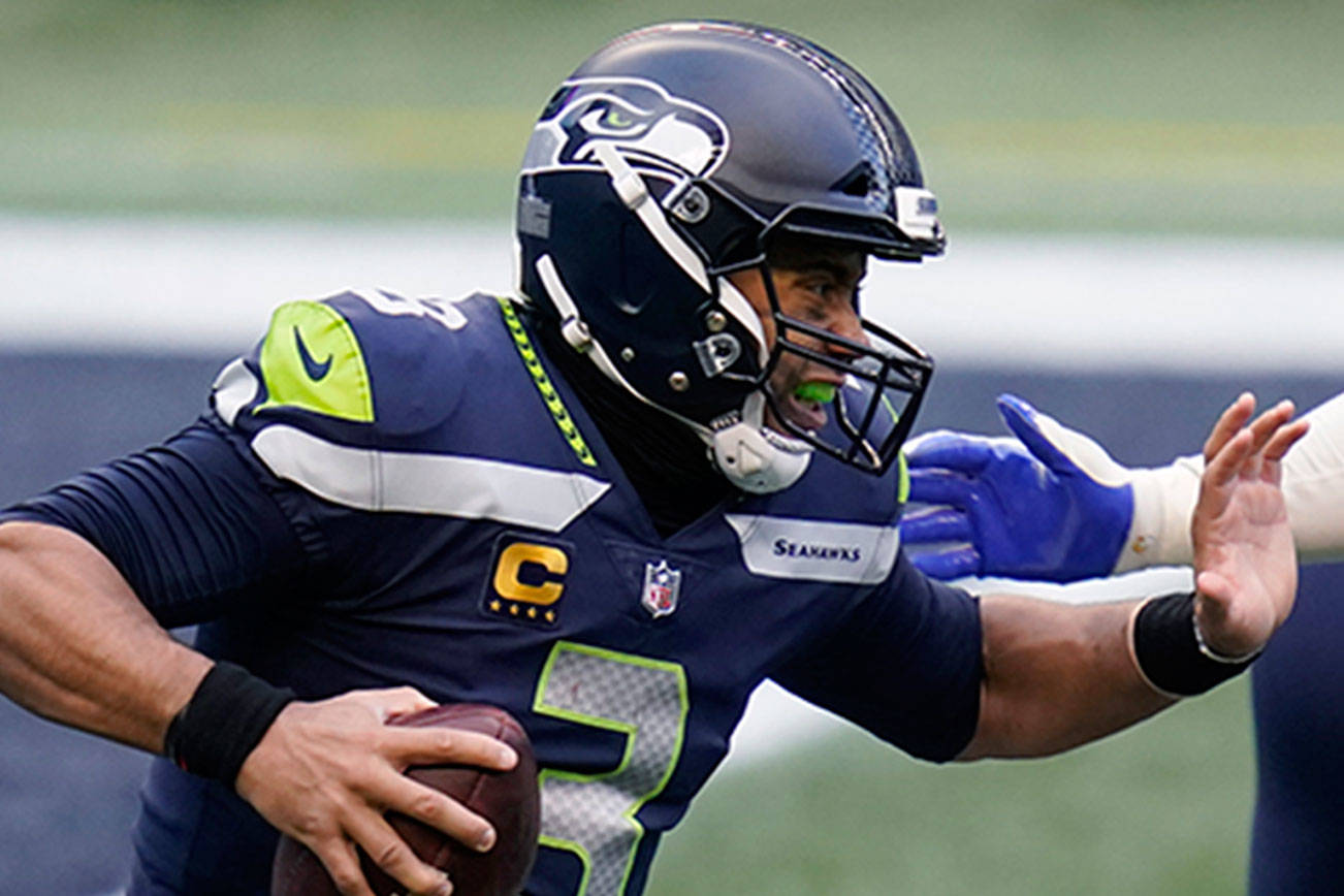 Seattle Seahawks quarterback Russell Wilson (3) tries to fend off a sack by Los Angeles Rams defensive lineman Aaron Donald (99) during the second half of an NFL football game Dec. 27 in Seattle. (Elaine Thompson/The Associated Press)