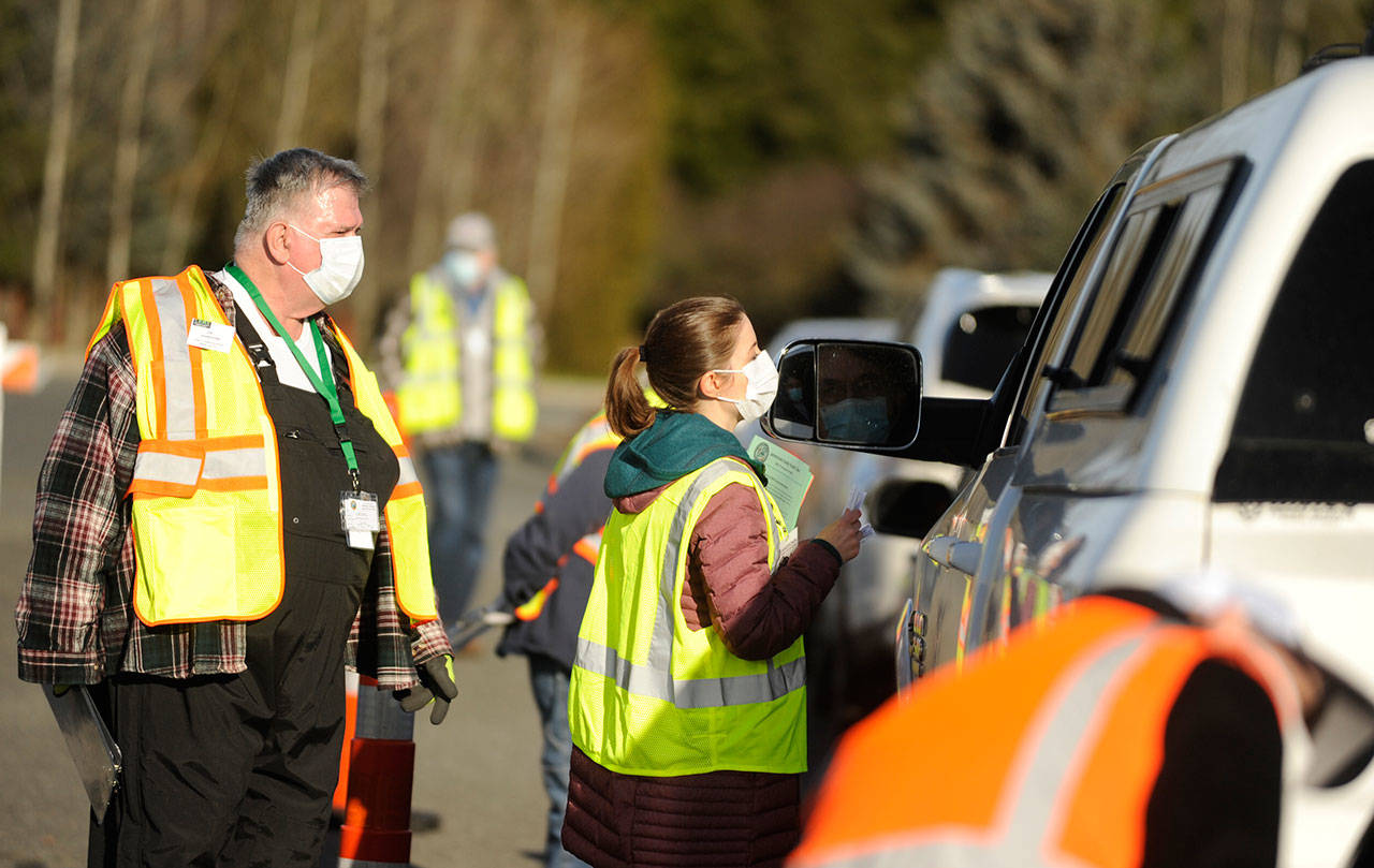 Dr. Molly Martin, deputy medical director at the Jamestown S’Klallam Tribe, and Community Emergency Response Team member Jim Johnston help individuals get registered for COVID-19 vaccinations at the tribe’s clinic on Jan. 14. Sequim Gazette photo by Michael Dashiell
