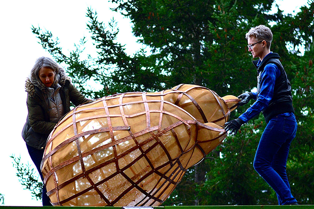 Port Angeles Fine Arts Center gallery and program director Sarah Jane, right, helps fellow artist Katherine Shaughnessy position her installation, "Tempest Tost," on the roof of the arts center in late 2019. The piece is back on the roof for this season's Wintertide show in and around the Webster's Woods park. (Diane Urbani de la Paz/Peninsula Daily News)