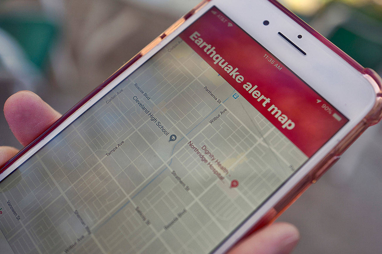 FILE - In this Jan. 3, 2019, file photo, a mobile phone customer looks at an earthquake warning application on an iPhone in Los Angeles. An earthquake early warning system operated by the U.S. Geological Survey has been activated in Oregon on the 10th anniversary of the devastating earthquake and tsunami in Japan. California already has the system. Washington state joins it in May, which will complete coverage of the West Coast of the contiguous United States. (AP Photo/Richard Vogel, File)