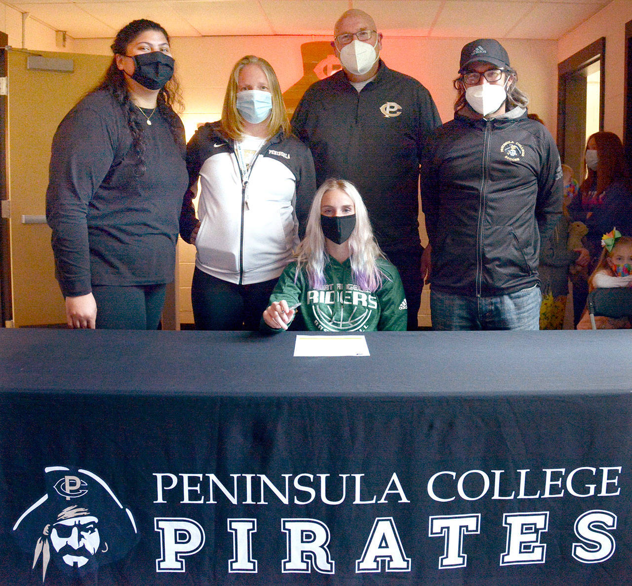 Port Angeles’ Millie Long, seated, prepares to sign her letter of intent to play soccer and basketball for Peninsula College. She is joined by, from left, Peninsula College women’s basketball assistant coach Gabi Fenumiai, head coach Alison Crumb, assistant coach Mike Knowles and women’s soccer head coach Kanyon Anderson. (Peninsula College Athletics)