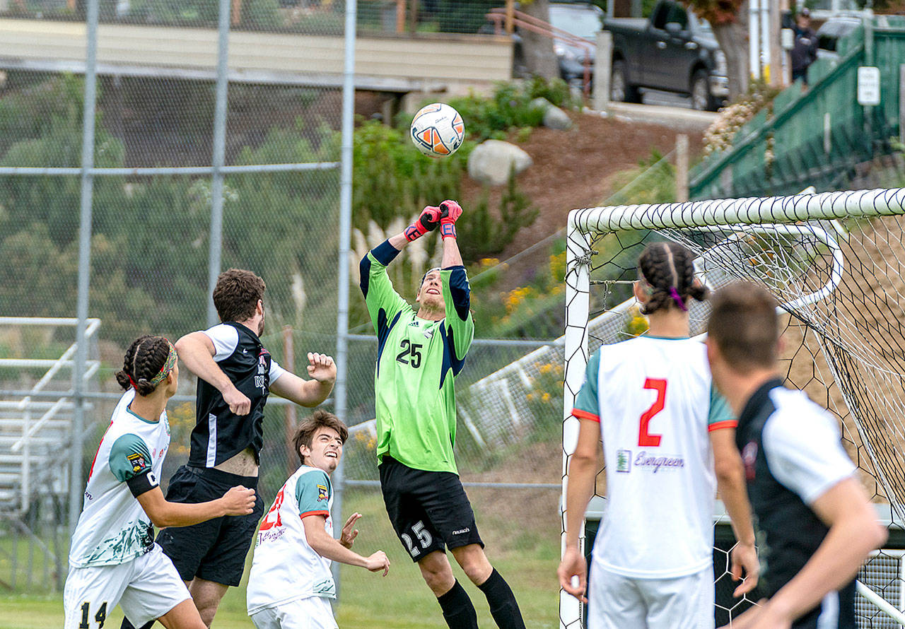 Northern Peninsula Football Club goalkeeper, Hayden Price (25), makes the save during a Western Washington Premier League 2 match Sunday against the Gala FC from Mill Creek played in Port Townsend’s Memorial Field. Teammates Silas DeWyse, 14, Raul Medina, 21 and Trillium DeWyse, 2, look on. (Steve Mullensky/for Peninsula Daily News)
