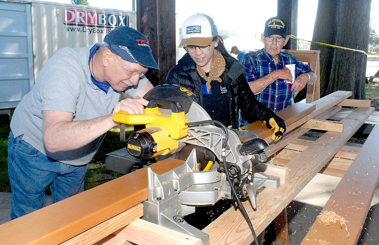 Volunteers, from left, John Albiso, Tien Vo and Bill Chastain cut boards that will become part of the Generation II Dream Playground during the first day of a six-day community build on Tuesday at Erickson Playfield in Port Angeles. The playground will replace an antiquated version that was built by volunteers in 2002 and torn down earlier this year. Organizers are still seeking volunteers to help with construction, the loan of woodworking tools and monetary donations. More information on the build is at www.padreamplayground.org. (Keith Thorpe/Peninsula Daily News)