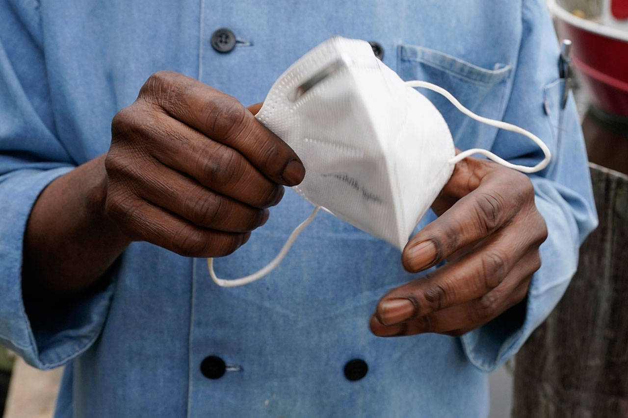 In this March 5 photo, a restaurant worker holds his face mask in Biloxi, Miss. The nation’s top health agency backpedaled on its masking guidelines and recommend that even vaccinated people wear masks indoors in parts of the U.S. where the coronavirus is surging. (Rogelio V. Solis/The Associated Press)
