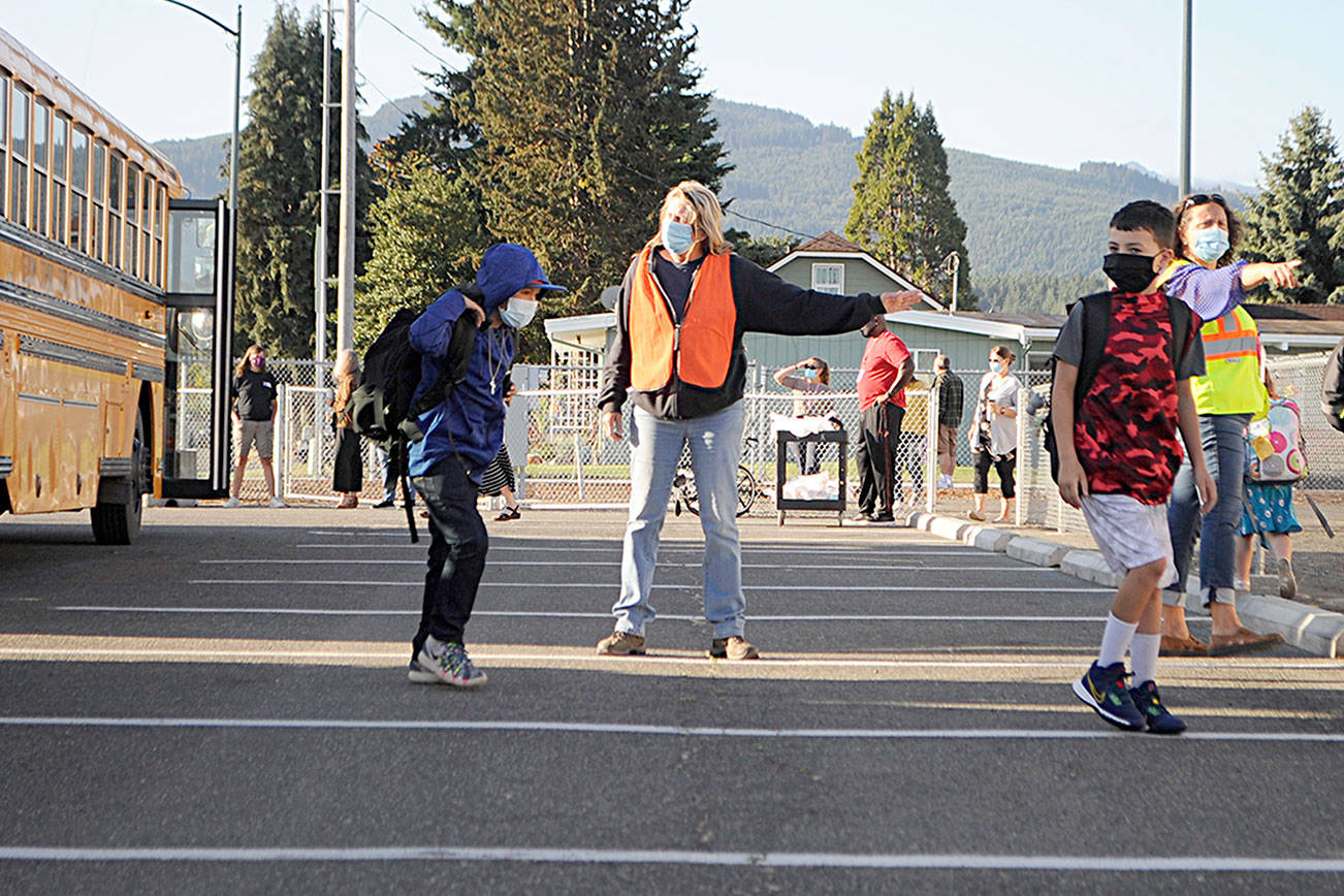 Bus driver Veronica Brenner, center, and paraeducator Liz Joers direct students to classrooms at Helen Haller Elementary and buses to Greywolf Elementary on Wednesday morning for the first day of school. (Matthew Nash/Olympic Peninsula News Group)