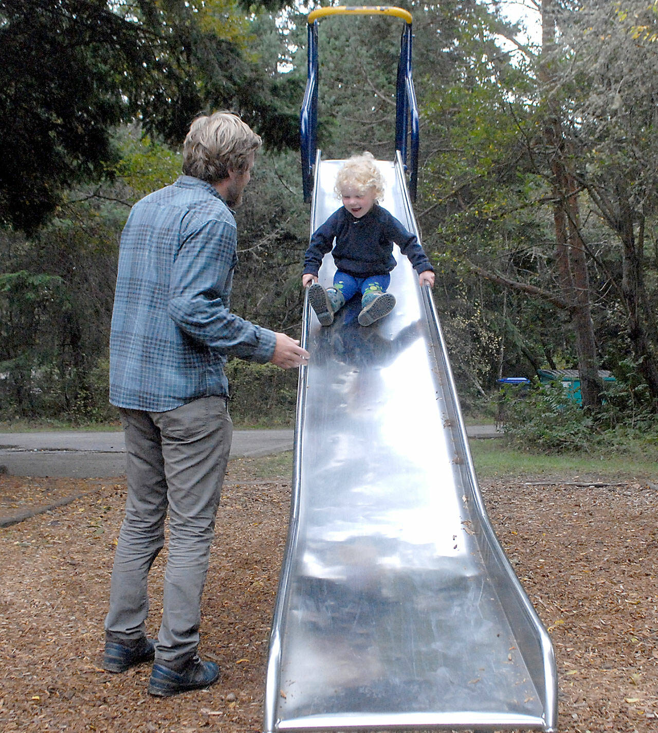 Glen Wade of Port Angeles encourages his son, Yuli Schutz-Wade, 2 1/2, to go down a tall slide on Thursday on the playground at Dungeness Recreation Area north of Sequim. The area is a popular spot to camp and hike, and provides access to Dungeness Spit and the Dungeness National Wildlife Refuge. (Keith Thorpe/Peninsula Daily News)
