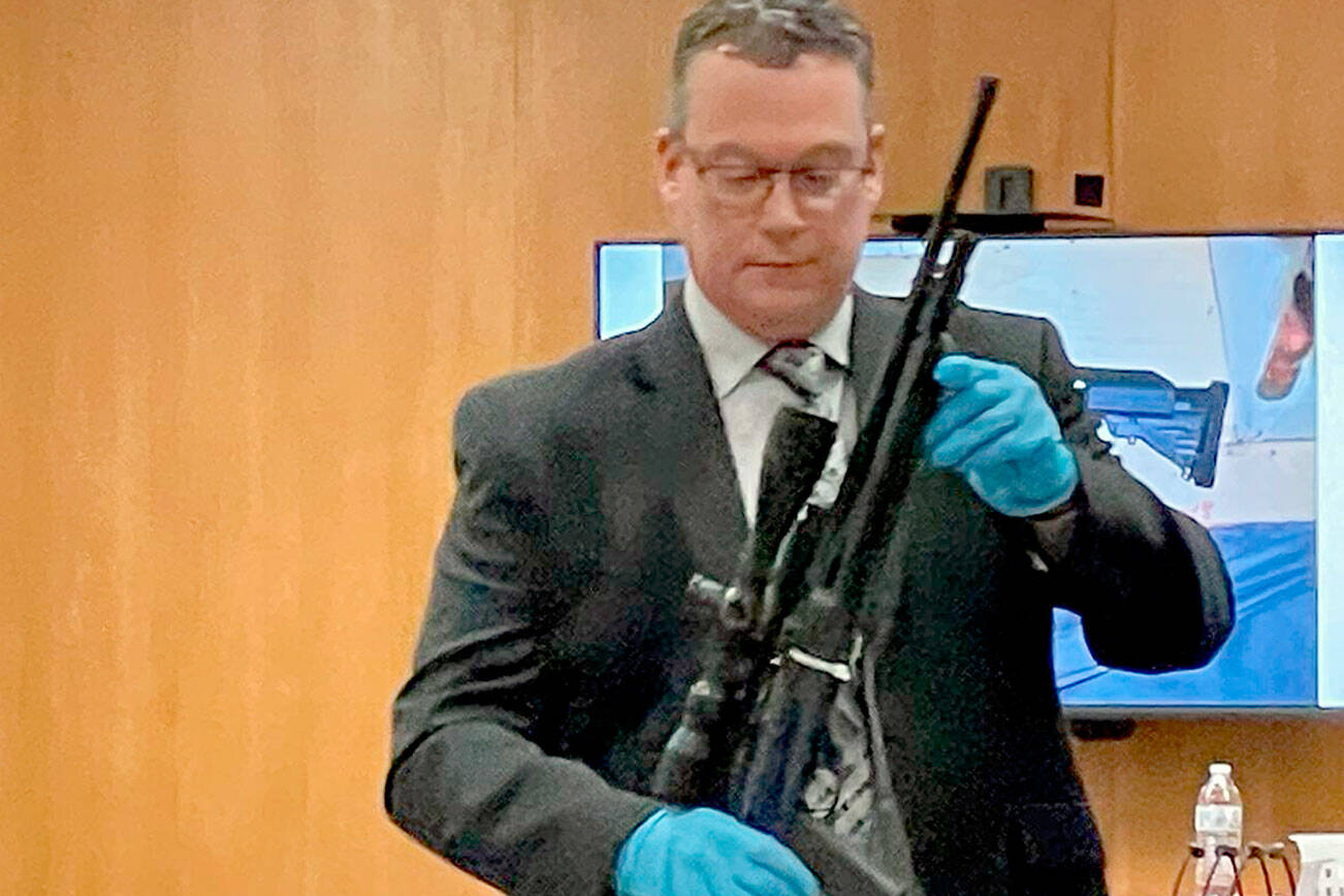 Detective Sgt. Eric Munger of the Clallam County Sheriff’s Office prepares to show a semi-automatic rifle presented in the triple-murder trial of Dennis Marvin Bauer. (Paul Gottlieb/Peninsula Daily News)