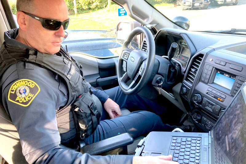 Lynnwood police Officer Denis Molloy works in his vehicle in November. Molloy, of the Lynnwood Police Department’s community health and safety section, says navigating recent police reforms in Washington State has been challenging. (Gene Johnson/The Associated Press)