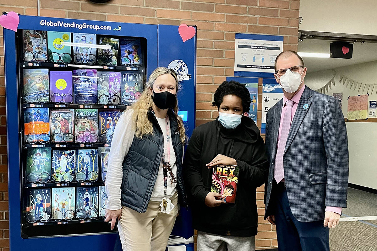 Principal Kristen Lunt (left), Student Lyndel Atwater, and Superintendent Marty Brewer. Lyndel who earned his token for the Inchy Bookworm Vending Machine by cleaning up sporting equipment after a football game without having to be asked.