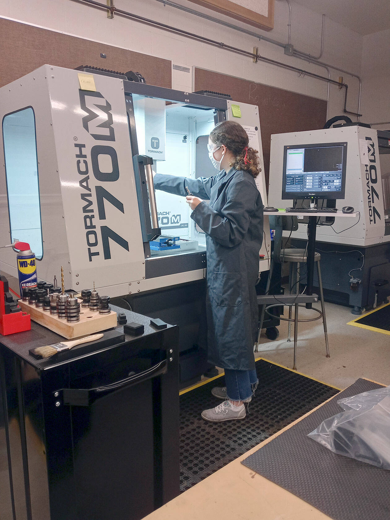 Port Townsend High School senior Haley Jones operates a computer-numeric control (CNC) milling machine, one of the pieces of equipment she learned to use in Tim Behrenfeld’s computer-integrated manufacturing course. (photo by Tim Behrenfeld)