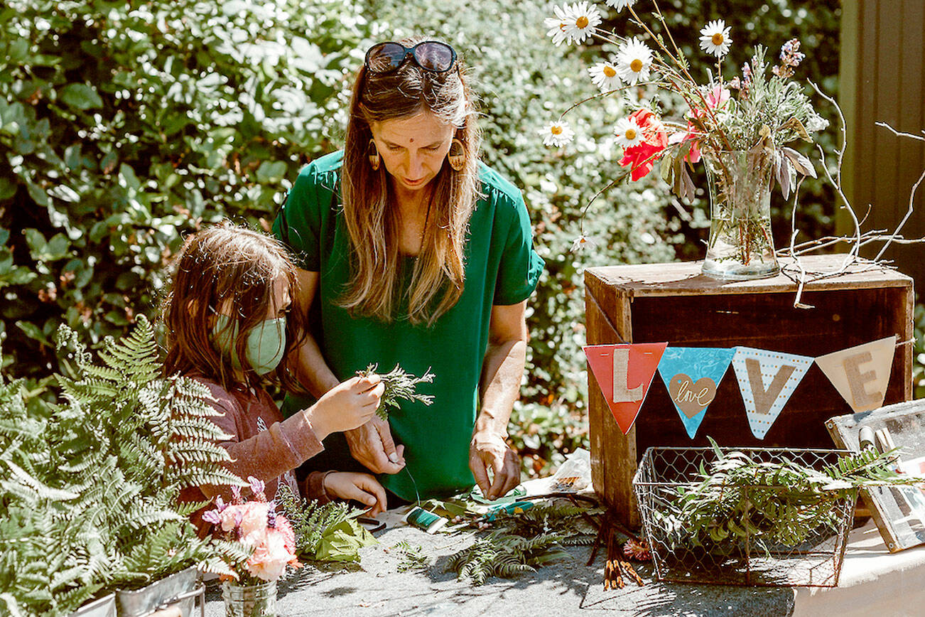 Christine Loewe, executive director of the Port Angeles Fine Arts Center, makes flower crowns with Theo Miller in this file photo. The annual celebration will be on Saturday.
