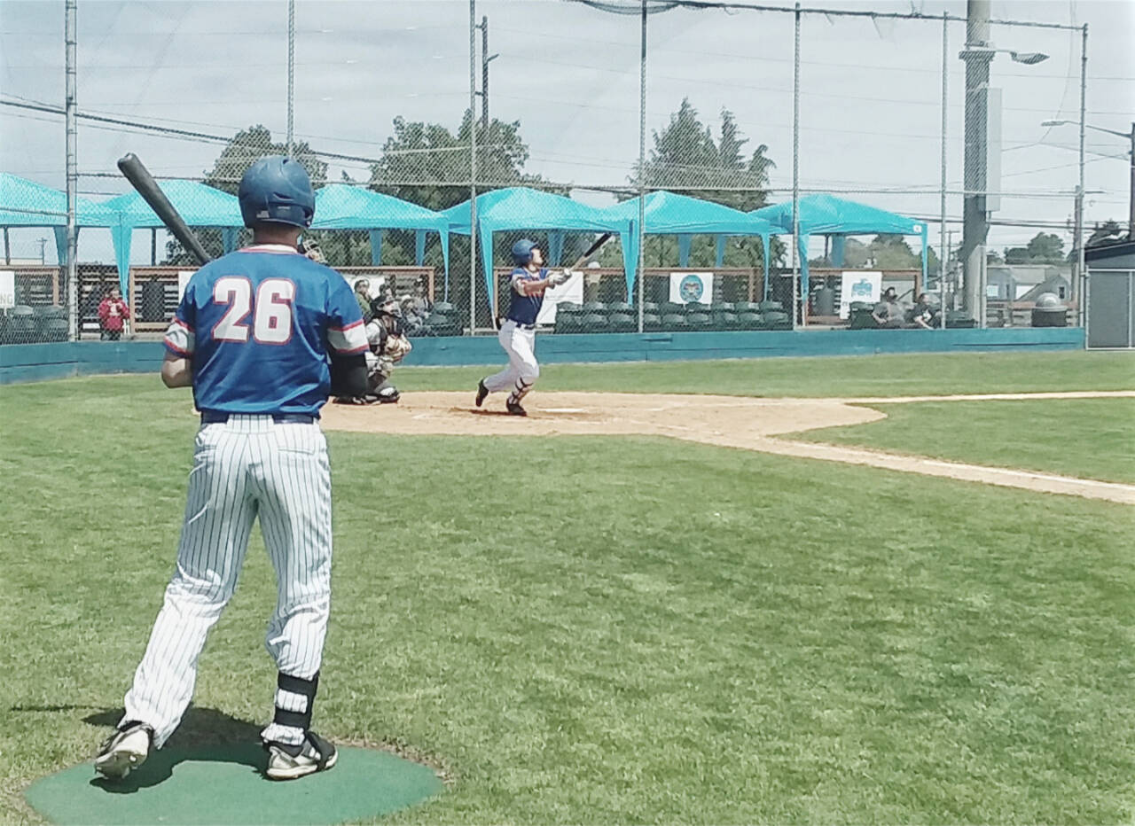 The Port Angeles Lefties’ BY Choi hits a fly ball foul as former Port Angeles Roughrider Ethan Flodstrom (26) waits in the on-deck circle Sunday at Civic Field. (Pierre LaBossiere/Peninsula Daily News)