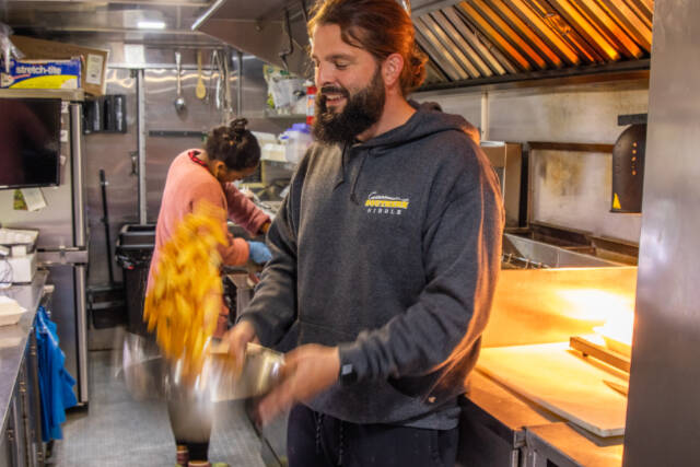 Caleb Messinger of the Southern Nibble tosses french fries to coat them evenly with salt. Emily Matthiessen/Olympic Peninsula News Group