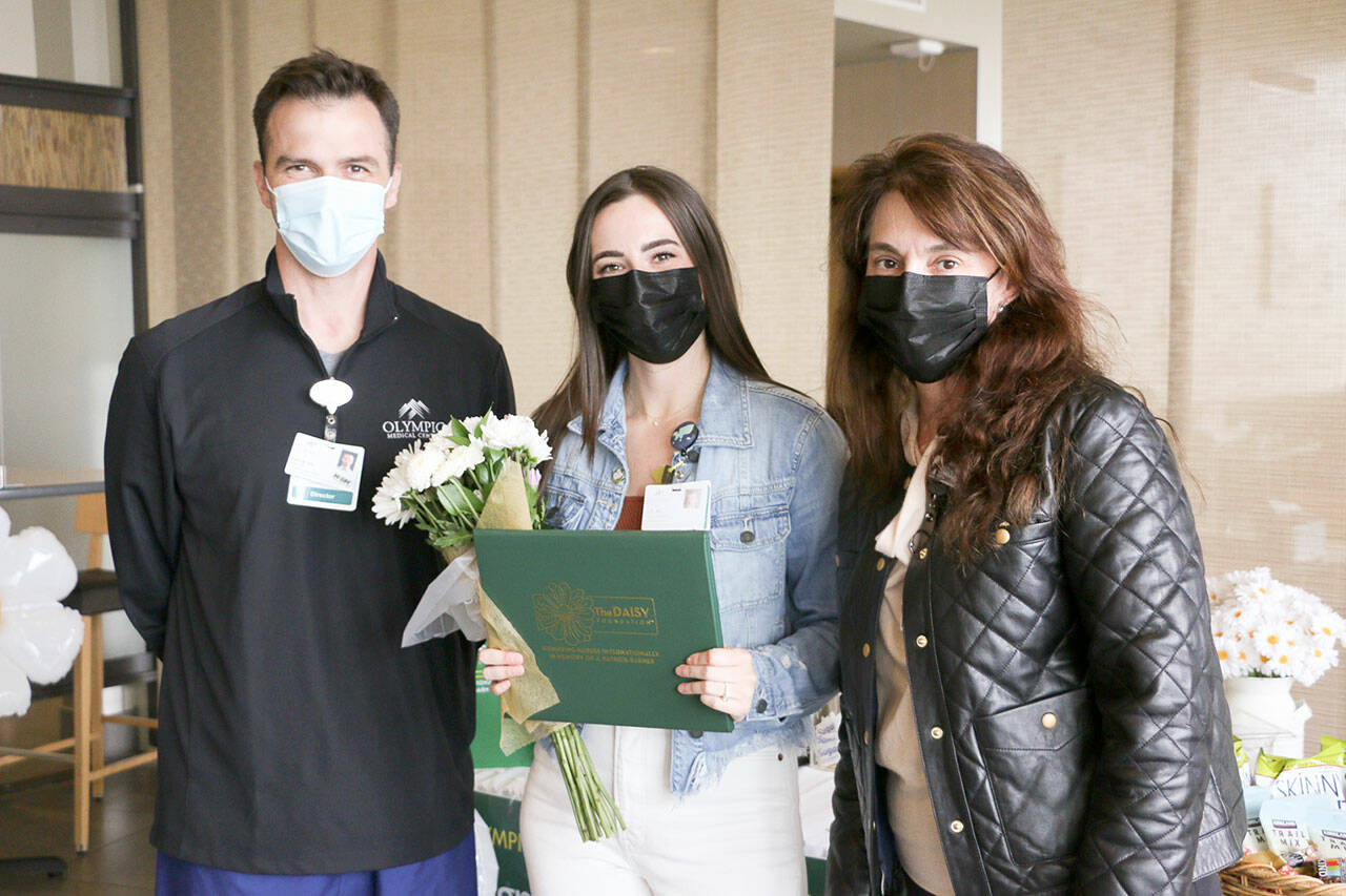 Aaron Possin, left, and Vickie Swanson, right, present a DAISY Award to Elizabeth Hornsey, an RN in Olympic Medical Center’s emergency department.
