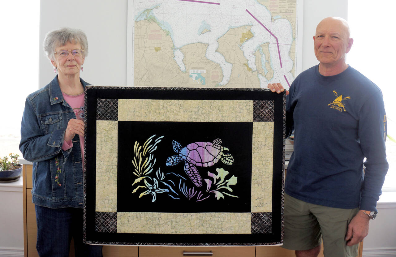 Mary Jeanne Richards and club Commodore Frank DeSalvo of the Sequim Bay Yacht Club display “The Spirit of Honu,” a quilt being raffled by the club to raise funds for Volunteer Hospice of Clallam County respite care services.