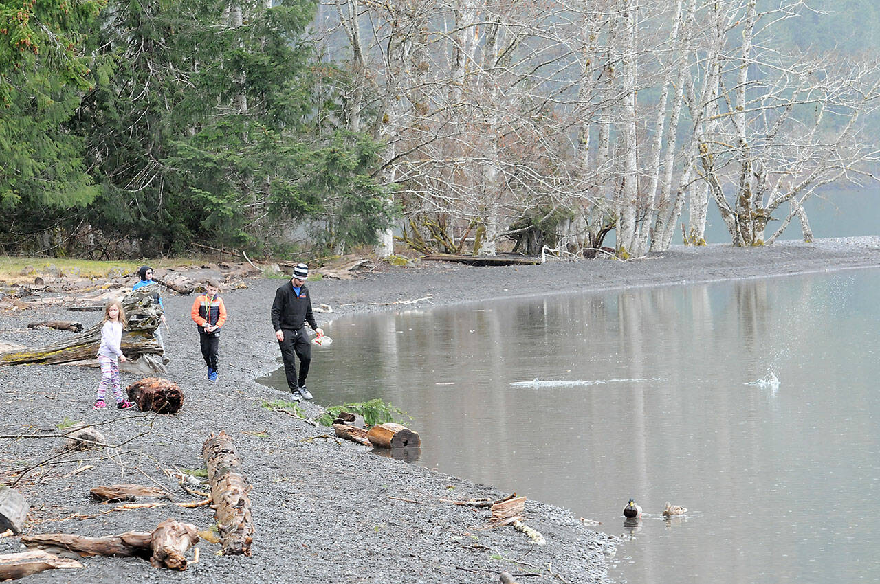 Jerry DeShazer of Ridgefield, right, along with family members, from left, Macklyn DeShazer, 6, Jace DeShazer, 11, and Jantzen DeShazer, 10, walk and skip rocks along the shore of Lake Crescent at Barnes Point in Olympic National Park. The family was on an outing to the North Olympic Peninsula with a visit to the park along the way. (Keith Thorpe/Peninsula Daily News)