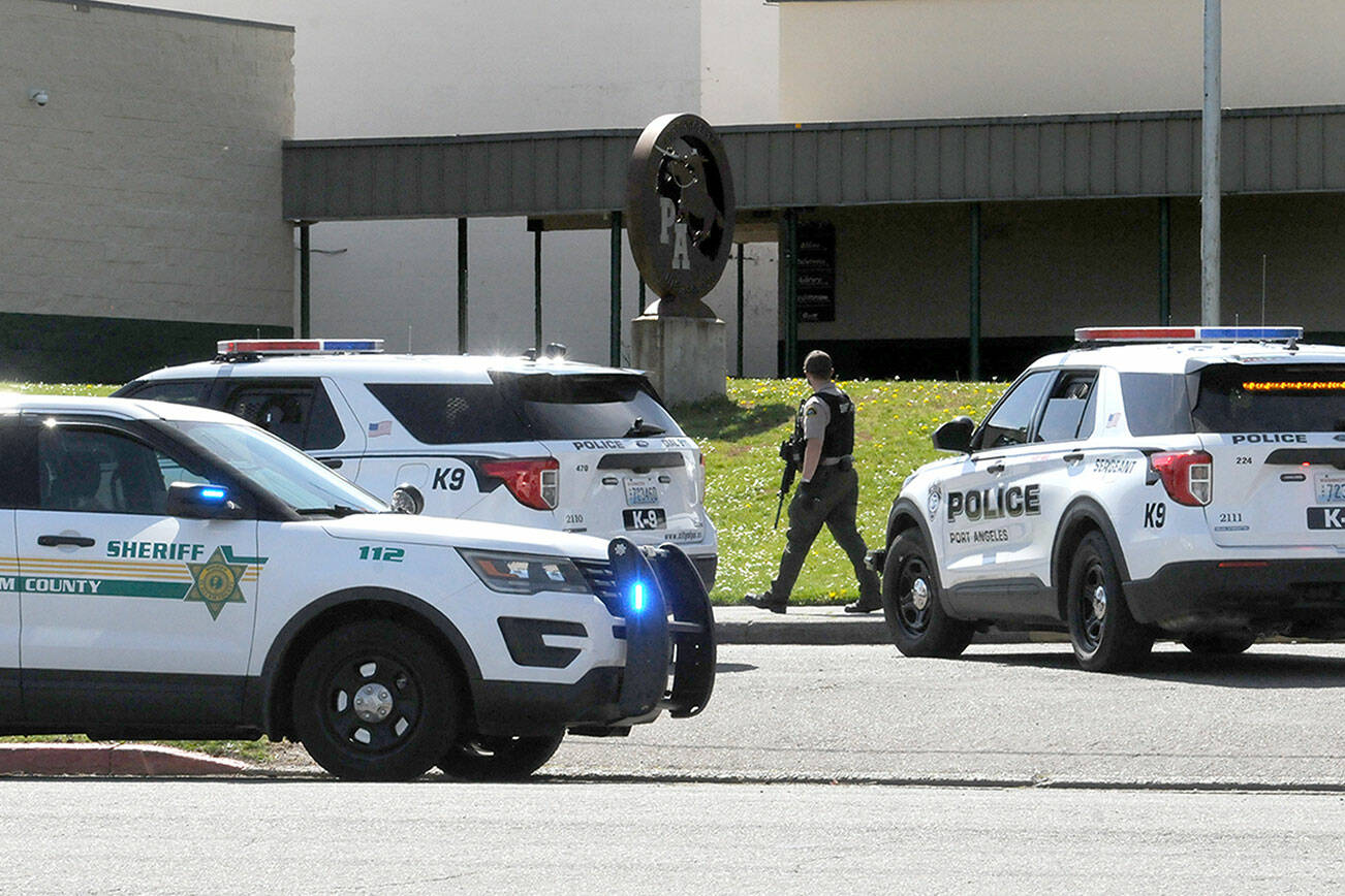 An armed Clallam County sheriff’s deputy walks near the entrance of Port Angeles High School after a telephone threat was made to the school on Thursday. (Keith Thorpe/Peninsula Daily News)