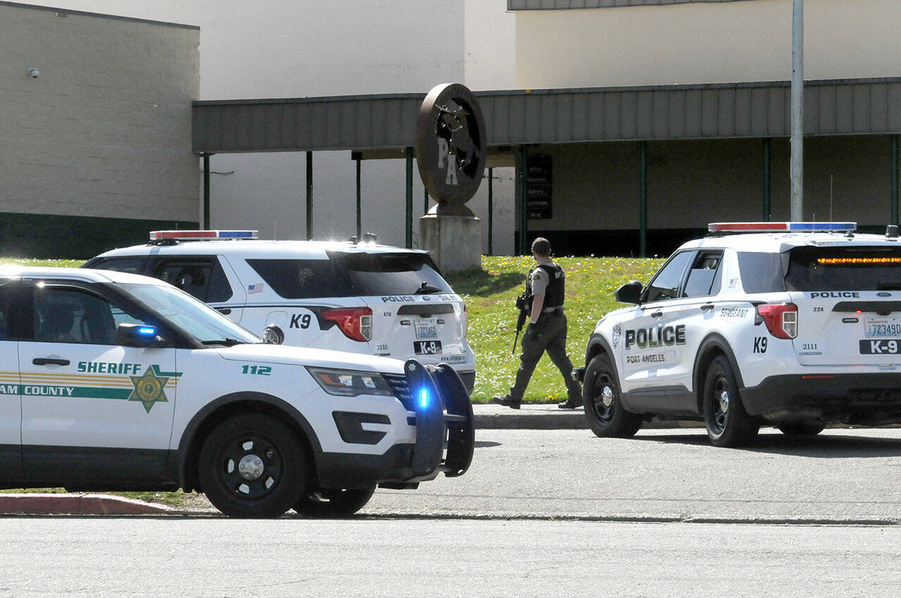 An armed Clallam County sheriff’s deputy walks near the entrance of Port Angeles High School after a telephone threat was made to the school on Thursday. (Keith Thorpe/Peninsula Daily News)
