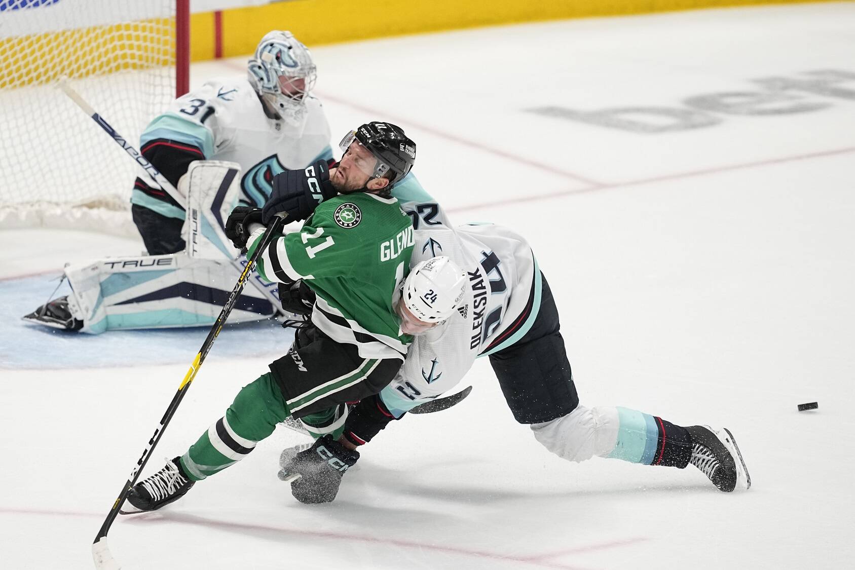 Dallas Stars center Luke Glendening (11) is knocked down on an attack by Seattle Kraken defenseman Jamie Oleksiak (24) as Kraken goaltender Philipp Grubauer (31) defends against the puck in the third period of Game 7 of an NHL hockey Stanley Cup second-round playoff series, Monday, May 15, 2023, in Dallas. (AP Photo/Tony Gutierrez)