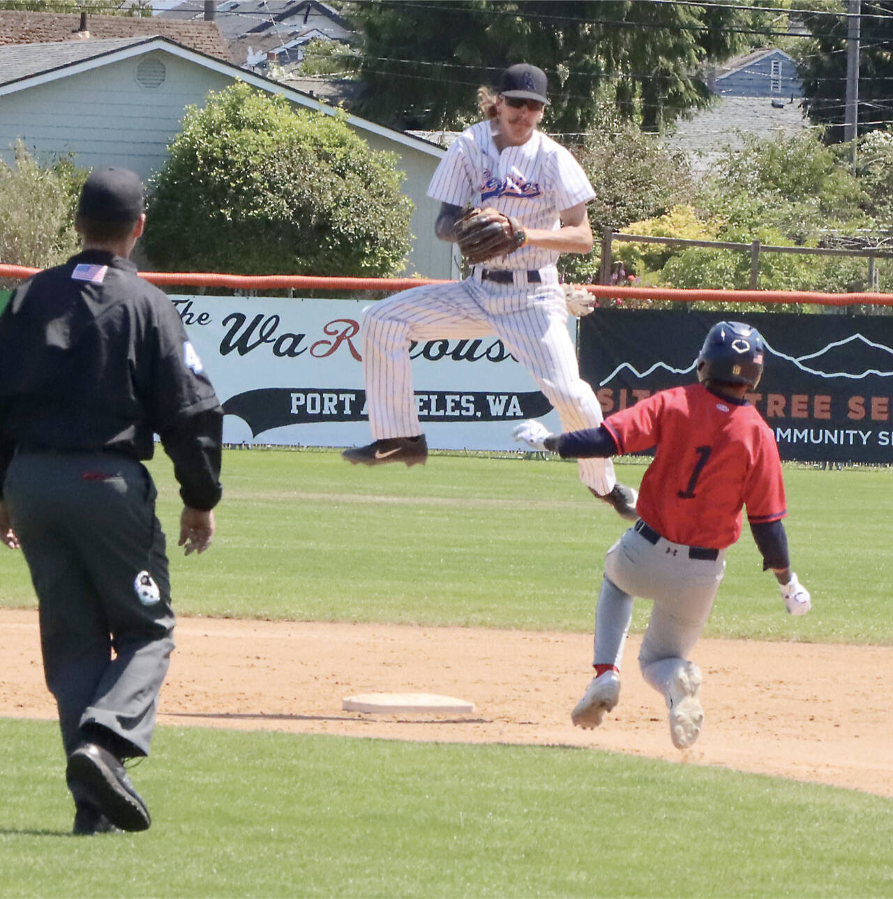 Port Angeles Lefties second baseman Robert Nunez jumps to catch a throw but isn’t able to punch out Kelowna baserunner Eddie Fines on Sunday at Civic Field. (Dave Logan/for Peninsula Daily News)