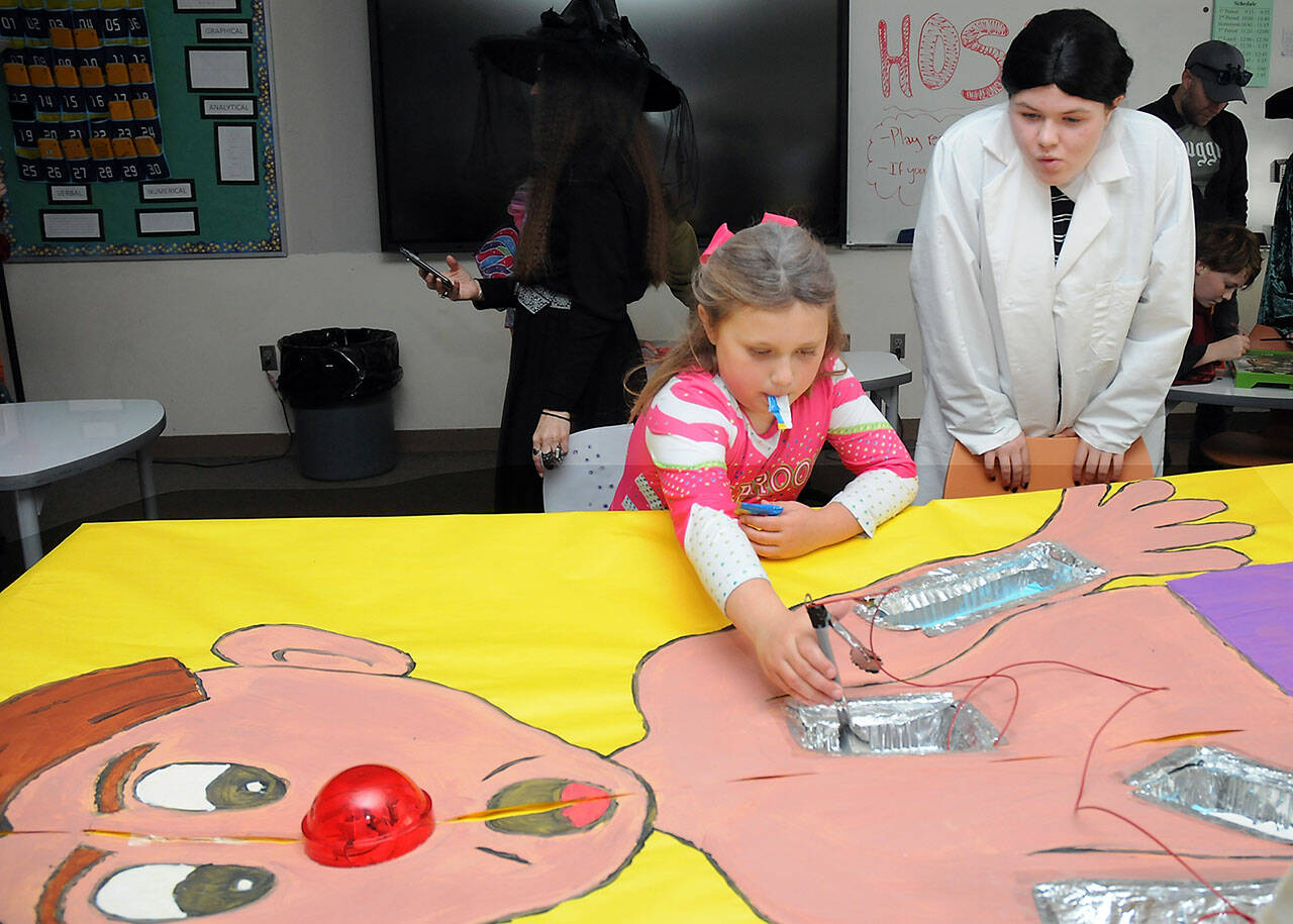 Sonnie Fountain, 8, of Sequim plays an oversized version of the Operation game under the direction of Sequim High School freshman Lillian Anderson during Saturday’s Haunted Hallways holiday event at the school. Haunted Hallways featured a portion of the school set aside for a variety of Halloween games and attractions hosted by students as a benefit for the Sequim Food Bank. (Keith Thorpe/Peninsula Daily News)