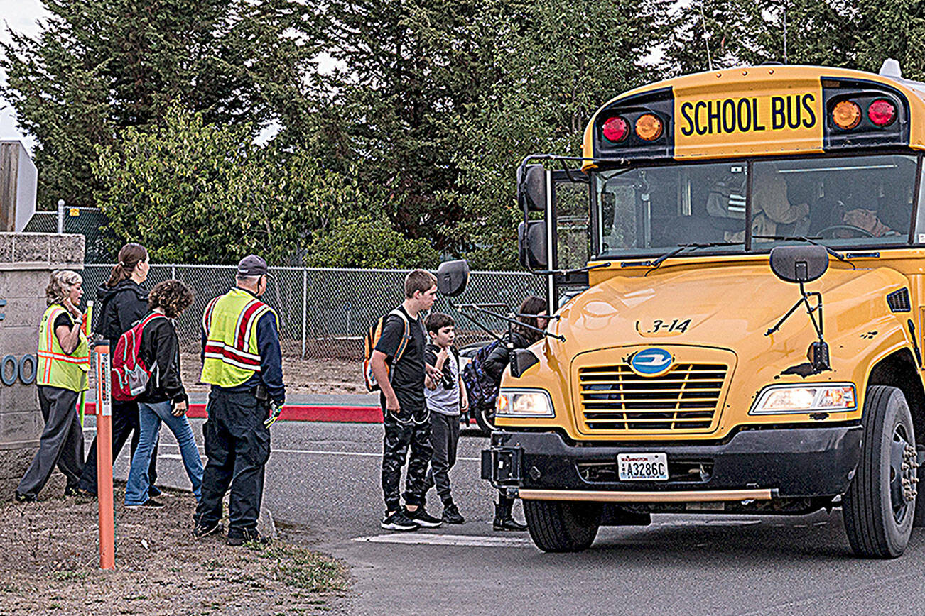 Community Emergency Response Team (CERT) members help students ride the bus in September while helping direct traffic for parents at drop-off/pick-up for the K-2, 3-5 reconfiguration of Greywolf and Helen Haller elementary schools. Sequim School District officials have started conversations to consider changing bus routes to improve attendance and behavior, among other things. (Michael Dashiell/Olympic Peninsula News Group)