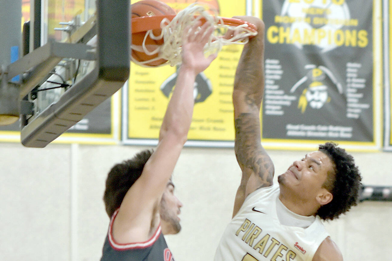 KEITH THORPE/PENINSULA DAILY NEWS 
Peninsula's Javon Ervin makes the slam dunk over the head of Olympic's Christian Parrish on Saturday in Port Angeles.