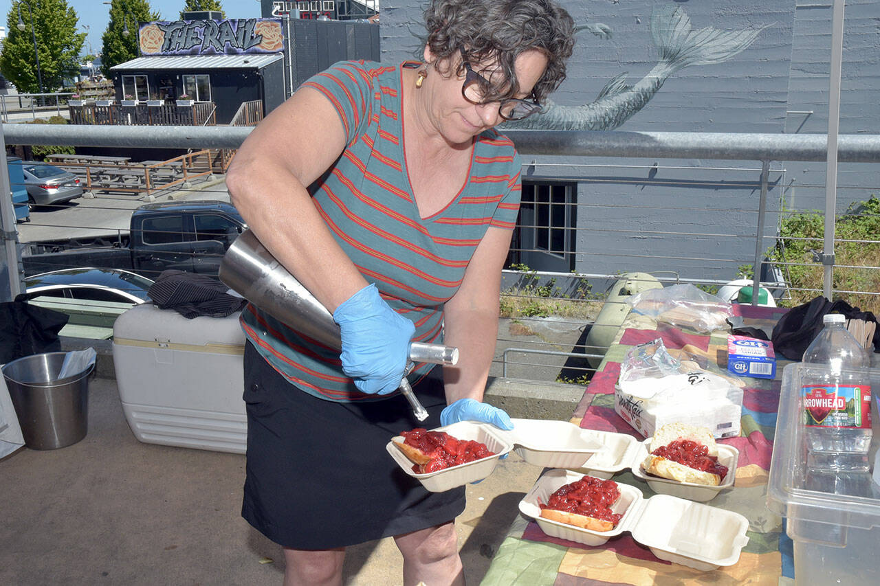 Port Angeles Farmers Market board member Vanessa Barrington adds whipped cream to a strawberry shortcake being sold at the market on Saturday as a fundraiser for market operations. Proceeds from shortcake sales help pay for insurance, organization memberships, rental fees, printing, postage and payroll for market staff. (Keith Thorpe/Peninsula Daily News)